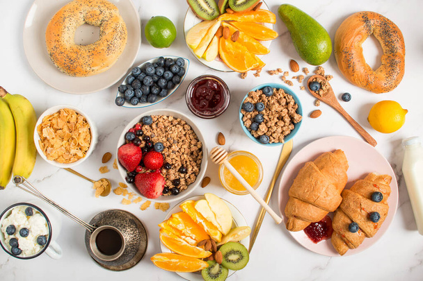 Ingredients for a healthy breakfast, nuts, oatmeal, honey, berries, fruits, blueberry, almonds, walnuts. The concept of natural organic food in season. Top view - Photo, Image