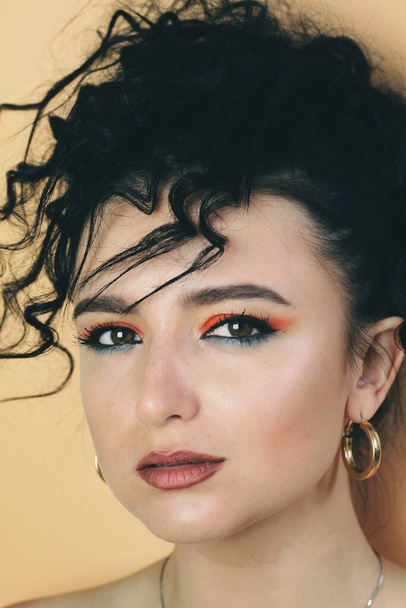 Όμορφη νεαρή μελαχρινή μοντέλο με φωτεινό μακιγιάζ και σγουρά χτένισμα - Φωτογραφία, εικόνα