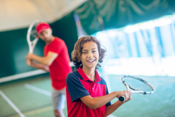 Coach in a red cap and a boy spending time playing tennis - Φωτογραφία, εικόνα