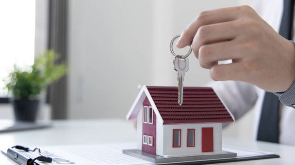 Értékesítési menedzser vagy ingatlanügynök készül átadni a kulcsokat és a ház együtt a biztosítás az ügyfél, Figyelem az ingatlan szolgáltatások és a biztosítási koncepció. - Fotó, kép