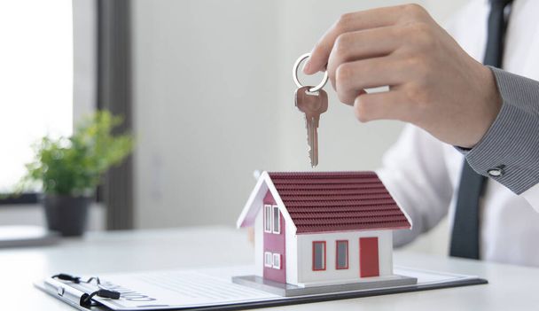 Kierownik sprzedaży lub agent nieruchomości przygotowuje się do przekazania kluczy i domu wraz z ubezpieczeniem do klienta, Uwaga na usługi nieruchomości i koncepcji ubezpieczenia. - Zdjęcie, obraz