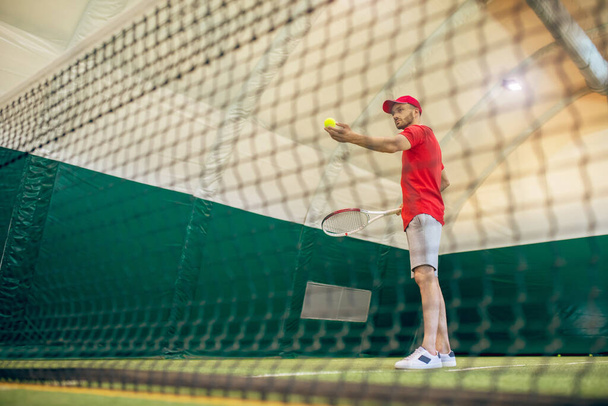 Young bearded man in a red cap ready to hit the tennis ball - Foto, Imagem
