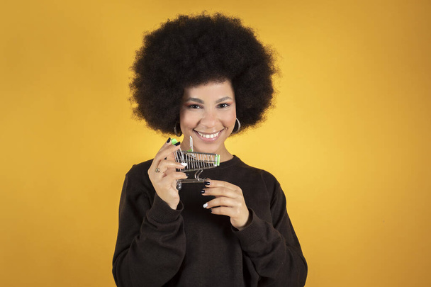 Счастливая смешанная афро-женщина улыбается, с мини-шопингом, - Фото, изображение