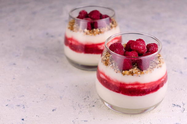 Dessert al lampone con yogurt greco e granola su un piatto bianco. Copia spazio. - Foto, immagini