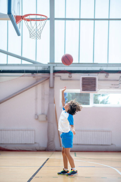 Dark-haired boy in sportswear throwing the ball into the ring - Φωτογραφία, εικόνα