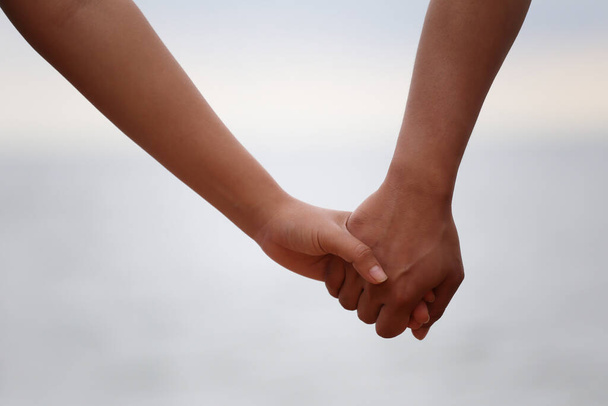 Ζευγάρι κρατώντας το χέρι σε ένα ελαφρύ υπόβαθρο σε Ιδέες για την αγάπη και την εποχή του Αγίου Βαλεντίνου. - Φωτογραφία, εικόνα