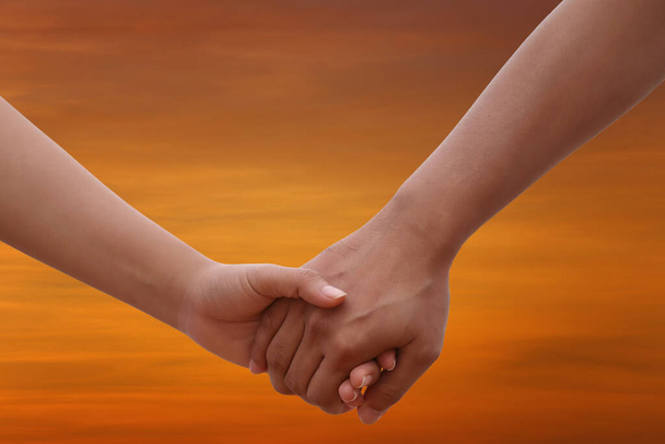 Young people holding hands on twilight sky background for design in valentine and couple concept. - Photo, Image