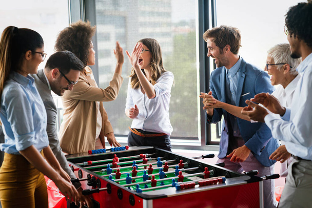 Business people having great time together. Colleagues playing table football in office - Foto, Imagen