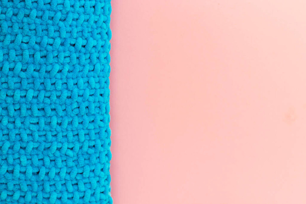 Μπλε πλεκτό παιδικό καρό στην αριστερή πλευρά. Μαλακή κουβέρτα σε ροζ φόντο. - Φωτογραφία, εικόνα