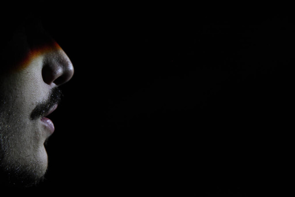 A male face with a mustache in the darkness - Фото, изображение