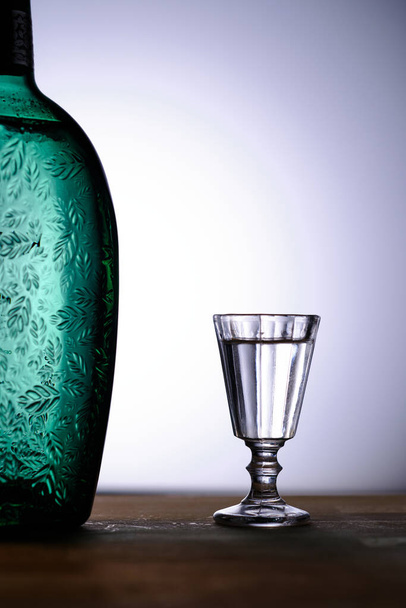 Un semplice bicchierino e un frammento di una bella bottiglia. Concentrazione selettiva. Spazio per lettering e design - Foto, immagini