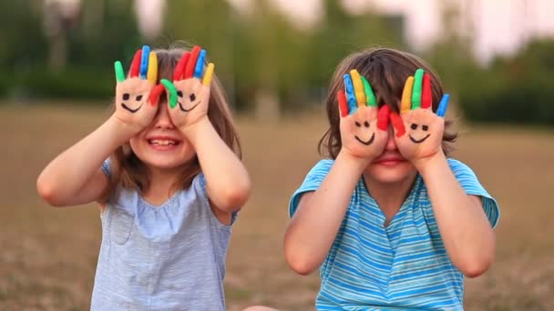 Due sorelle divertenti sorridono e salutano mani dipinte in estate - Filmati, video
