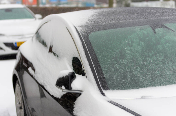 czarny zaparkowany samochód pokryty grubą warstwą lodu i śniegu na ulicy w Boskoop, Holandia - Zdjęcie, obraz