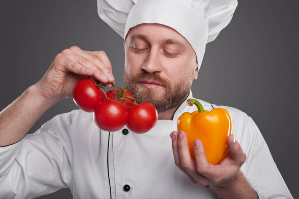 Bearded chef smelling fresh vegetables - 写真・画像
