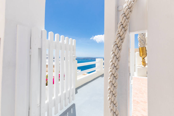 素晴らしい夏の旅行の背景。ギリシャのサントリーニ島で青い海の景色を望む白いフェンスと木製のドア。ラグジュアリーな旅とライフスタイル。ホテル、リゾートの外観、白い建築。幻想的な夏の気分 - 写真・画像
