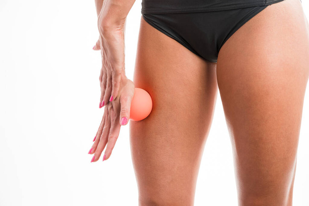 Una mujer atlética está masajeando sus músculos con la pelota - Foto, Imagen