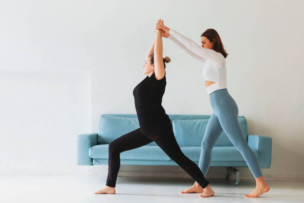 Mujer adulta ayudando a la mujer en ropa deportiva con hacer pose de yoga y brazos estirados - Foto, Imagen