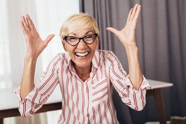 Portrét šťastné starší ženy gestikulující rukama doma. - Fotografie, Obrázek