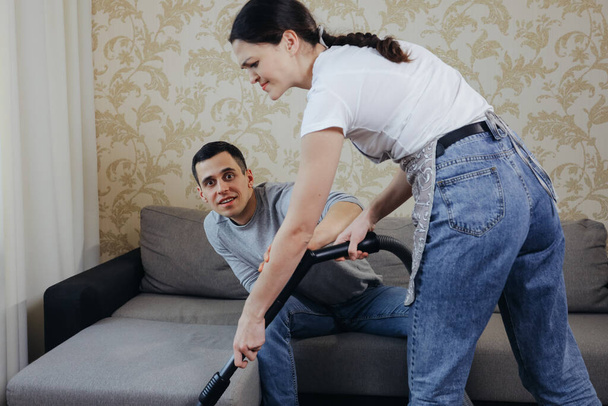 Wife vacuums the room and prevents her husband from watching TV - Foto, immagini