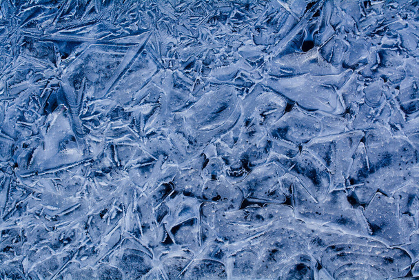 Foto van bevroren ijs in blauwe tinten. Winter natuurlijke achtergrond voor design. - Foto, afbeelding