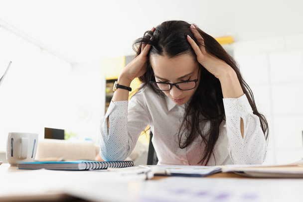 Tired woman bowed her head over her desk with documents - Foto, Imagen