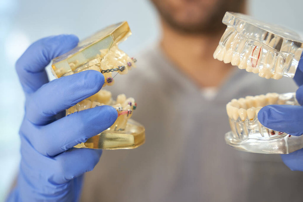 Zahnarzt mit Handschuhen demonstriert zwei Zähne - Foto, Bild