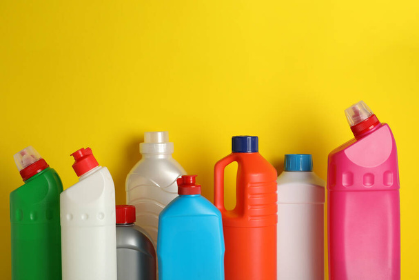 Пустые бутылки с различными моющими средствами на желтом фоне - Фото, изображение