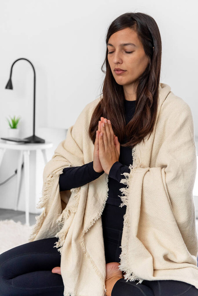 Frau in Aktivkleidung und Schal meditiert in Lotus-Pose mit namaste Hände während Yoga-Sitzung - Foto, Bild