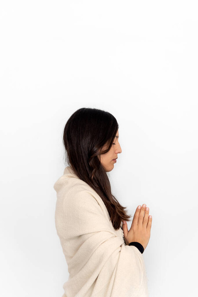 Жінка в активному одязі і шаль, роздумуючи з відмітками рук на білому тлі під час сеансу йоги
 - Фото, зображення