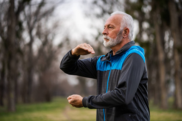 Vanhempi mies harjoittelee Tai Chi liikuntaa puistossa. - Valokuva, kuva