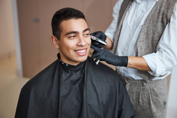 Przystojny mężczyzna relaksuje się przy zabiegu kosmetycznym w salonie fryzjerskim - Zdjęcie, obraz