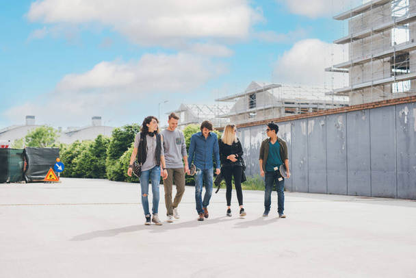 группа друзей многонациональная ходьба на открытом воздухе весело говорить друг с другом в подсветке весело и наслаждаясь хорошей компанией  - Фото, изображение