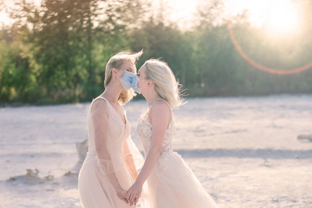 白い砂の上にレズビアンカップルの結婚式,流行を防ぐためにマスクを着用COVID-19 - 写真・画像