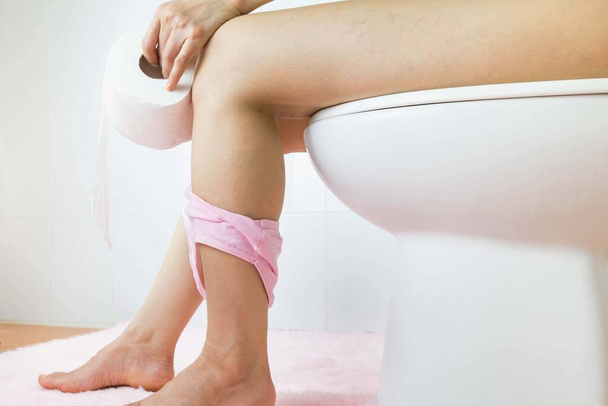 Selective focus Hand of woman in tissue bath sitting on toilet bowl. - Фото, зображення
