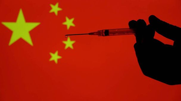 Europa, Itália, Milão - Vaccino anti Covid-19 Coronavirus e siringa con fondo di bandiere di vari paesi e nazioni alle prese con la somministrazione del vaccino- Cina- Whuan - Foto, Imagem