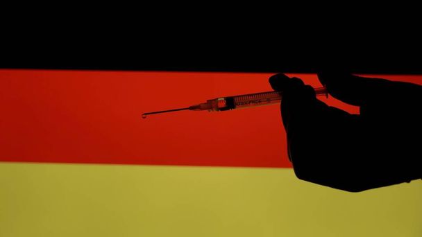 Europa, Italia, Milán - Vaccino anti Covid-19 Coronavirus e siringa con fondo di bandiere di vari paesi e nazioni alle prese con la somministrazione del vaccino- Germania Europa - Foto, imagen