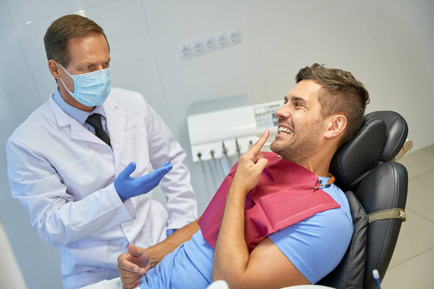 Mężczyzna pacjent i jego zaufany dentysta rozmawiający podczas kontroli - Zdjęcie, obraz