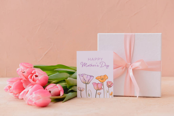 Hermosas flores, regalo y tarjeta de felicitación para el día de la madre en el fondo de color - Foto, Imagen