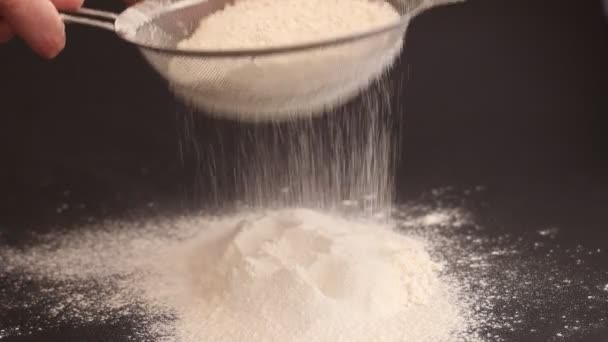Donna sta setacciando la farina attraverso setaccio per la cottura su sfondo nero - Filmati, video