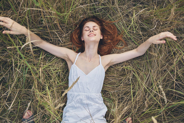 felice donna si trova su erba secca e gesti con le mani vestito bianco Copy Space - Foto, immagini