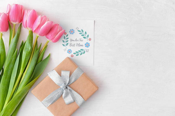 Hermosas flores, regalo y tarjeta de felicitación para el día de la madre sobre fondo blanco - Foto, imagen