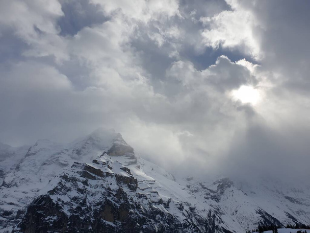 Άποψη των ελβετικών βουνών το χειμώνα. Ο 'ιγκερ στα σύννεφα, ο Μόνωχ και ο Γιούνγκφραου. Ελβετικές Άλπεις στην περιοχή Jungfrauregion της Ελβετίας - Φωτογραφία, εικόνα