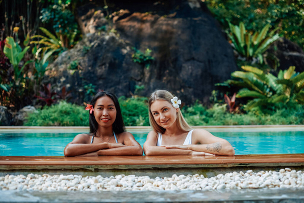 Дві щасливі жінки в басейні дивляться на камеру і посміхаються
 - Фото, зображення
