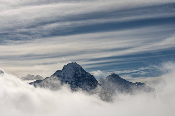 Uitzicht op de Zwitserse bergen in de winter. Eiger in de wolken, Monoch en Jungfrau. Zwitserse Alpen in Jungfrauregion in Zwitserland - Foto, afbeelding
