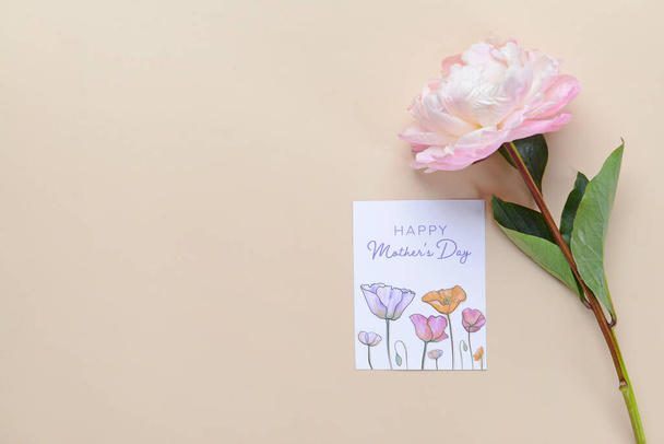 Hermosa flor y tarjeta de felicitación para el Día de la Madre sobre fondo de color - Foto, Imagen
