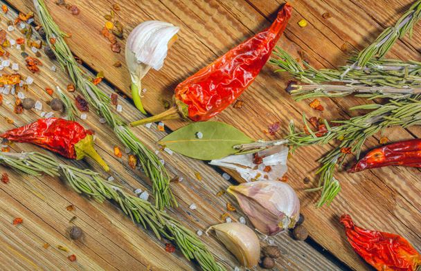 Spices, red chili pepper, garlic, peppercorns, paprika and rosemary sprigs on a wooden background background .Blurred focus. - Fotoğraf, Görsel