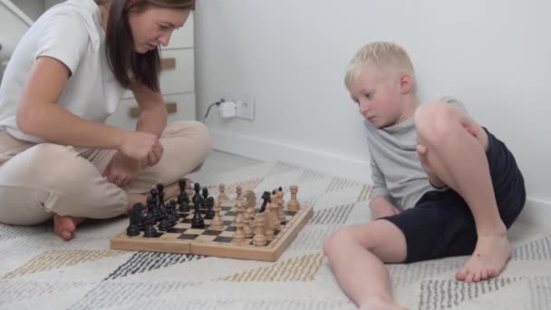 Mukava nainen pelaa shakkia lapsen kanssa kotona. - Materiaali, video