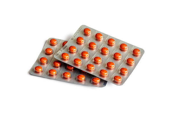 Comprimidos redondos de color marrón brillante en dos blísteres de aluminio, recetados por un médico, aislados sobre un fondo blanco - Foto, Imagen