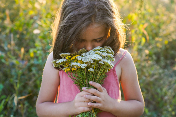 Portrait d'une petite fille avec des fleurs dans le champ. style de vie - Photo, image