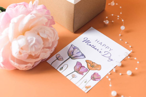 Красивый цветок, подарок и поздравительные открытки на День матери на цветном фоне - Фото, изображение